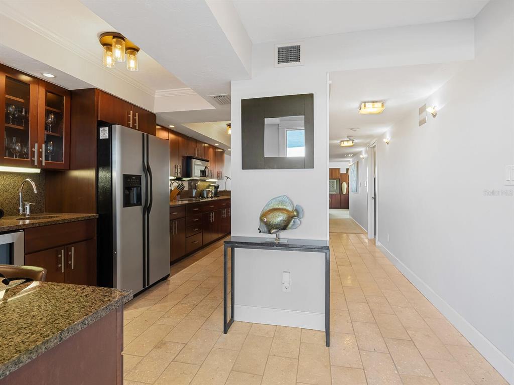 A kitchen with dark wood cabinets, granite countertops, and a stainless steel refrigerator — 5760 MIDNIGHT PASS ROAD UNIT 208D, SARASOTA, FL
