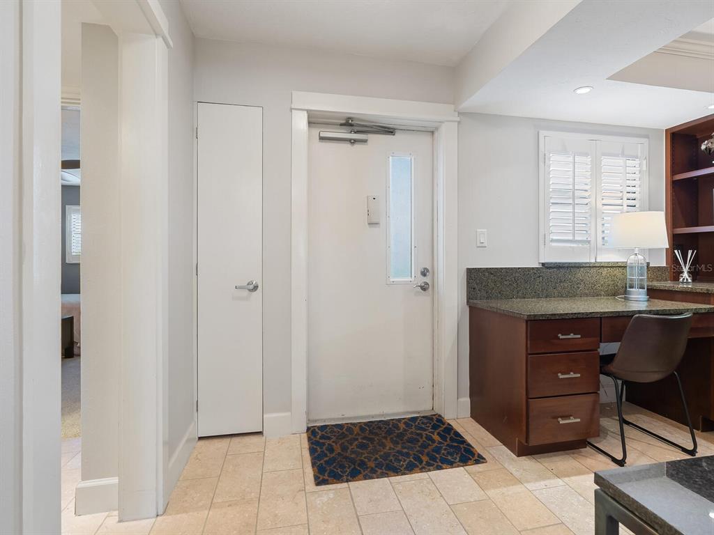 A room with a white door, a built-in desk, and light-colored tile flooring — 5760 MIDNIGHT PASS ROAD UNIT 208D, SARASOTA, FL