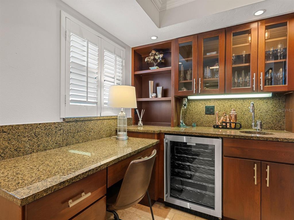 A wet bar features dark wood cabinetry, granite countertops, a wine cooler, and a desk area — 5760 MIDNIGHT PASS ROAD UNIT 208D, SARASOTA, FL