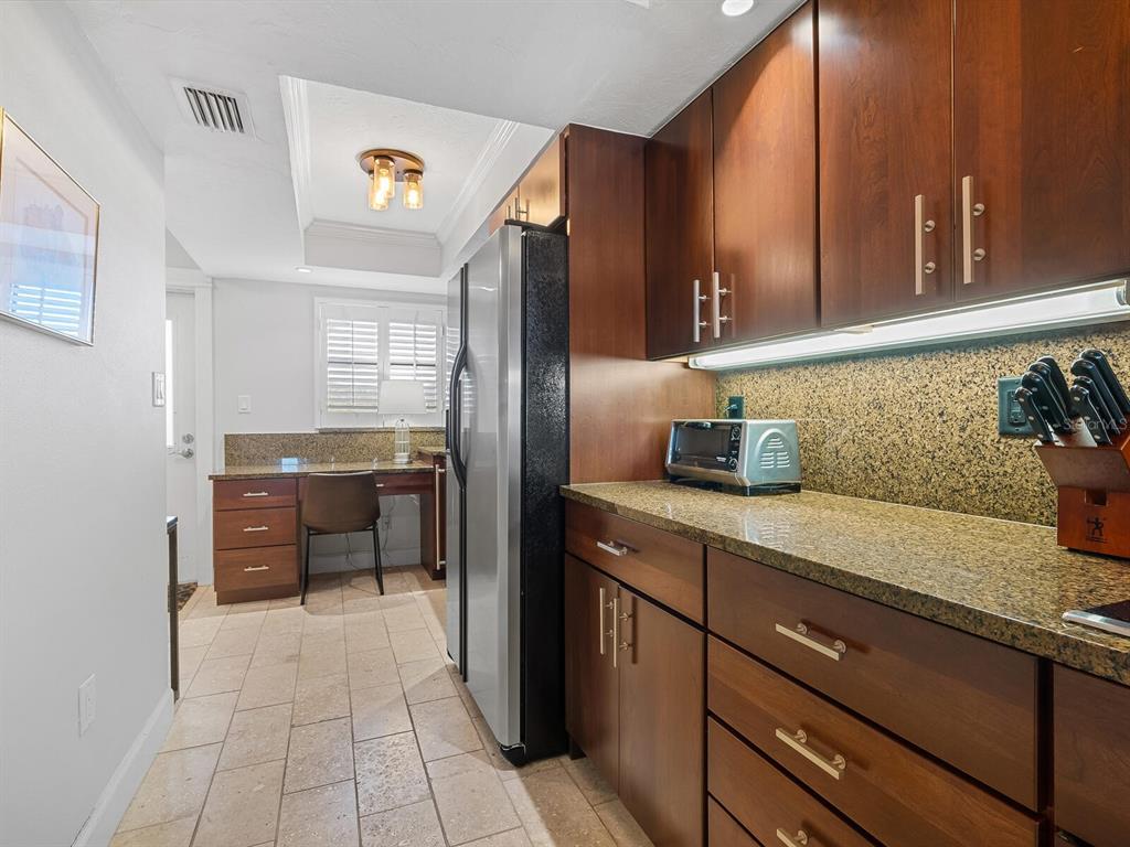 A kitchen features dark wood cabinets, granite countertops, stainless steel appliances, and a built-in desk — 5760 MIDNIGHT PASS ROAD UNIT 208D, SARASOTA, FL