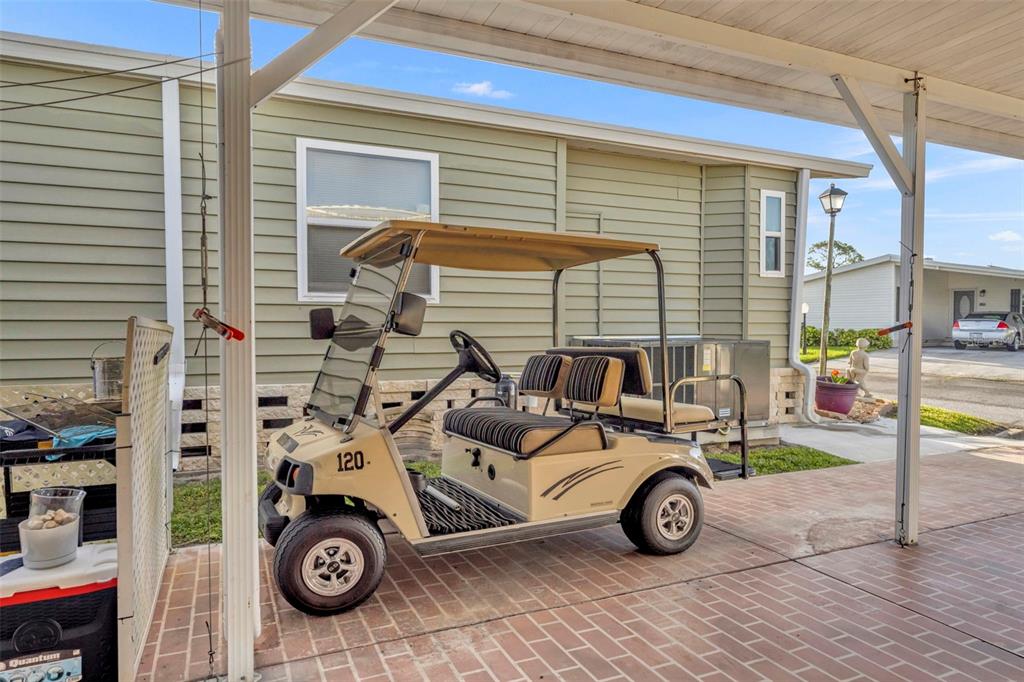 A tan golf cart is parked on a brick patio under a covered carport — 120 VICTORIA DRIVE, HAINES CITY, FL