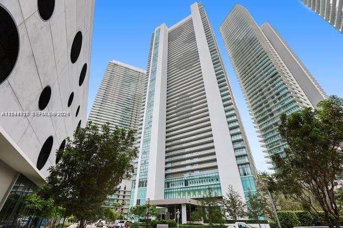 A low-angle view shows three tall, modern white residential skyscrapers against a clear blue sky — 650 NE 32nd St # 4205, Miami FL 33137, MIAMI, FL