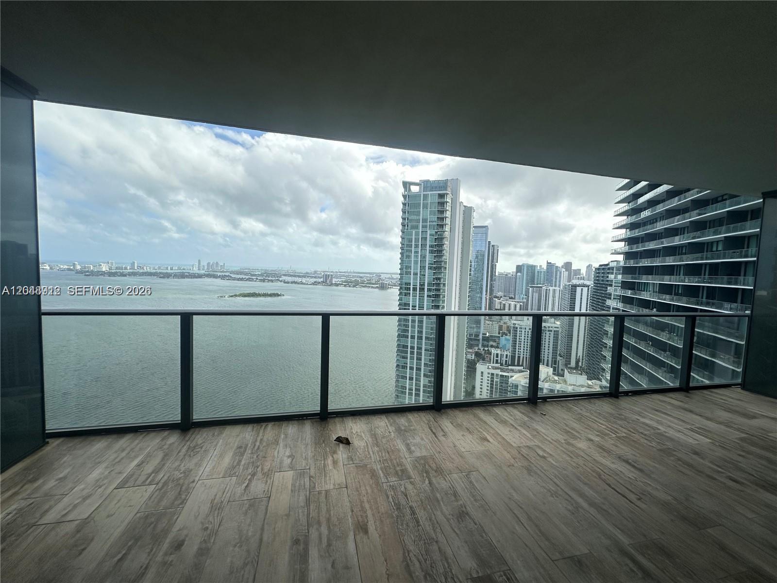 A balcony with wood-look tile flooring overlooks a bay and a city skyline — 650 NE 32nd St # 4205, Miami FL 33137, MIAMI, FL