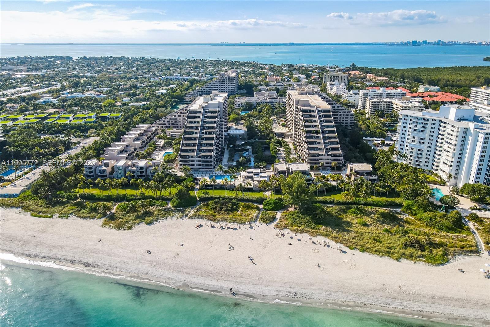 An aerial view shows beachfront condominiums with tiered balconies surrounded by lush landscaping and palm trees — 201 Crandon Blvd # 175, Key Biscayne FL 33149, KEY BISCAYNE, FL