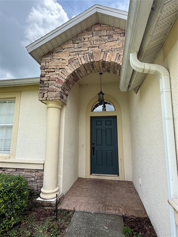 A front entryway features a stone-accented arch, a column, and a dark green door — 3806 WASHBURN PLACE, WESLEY CHAPEL, FL