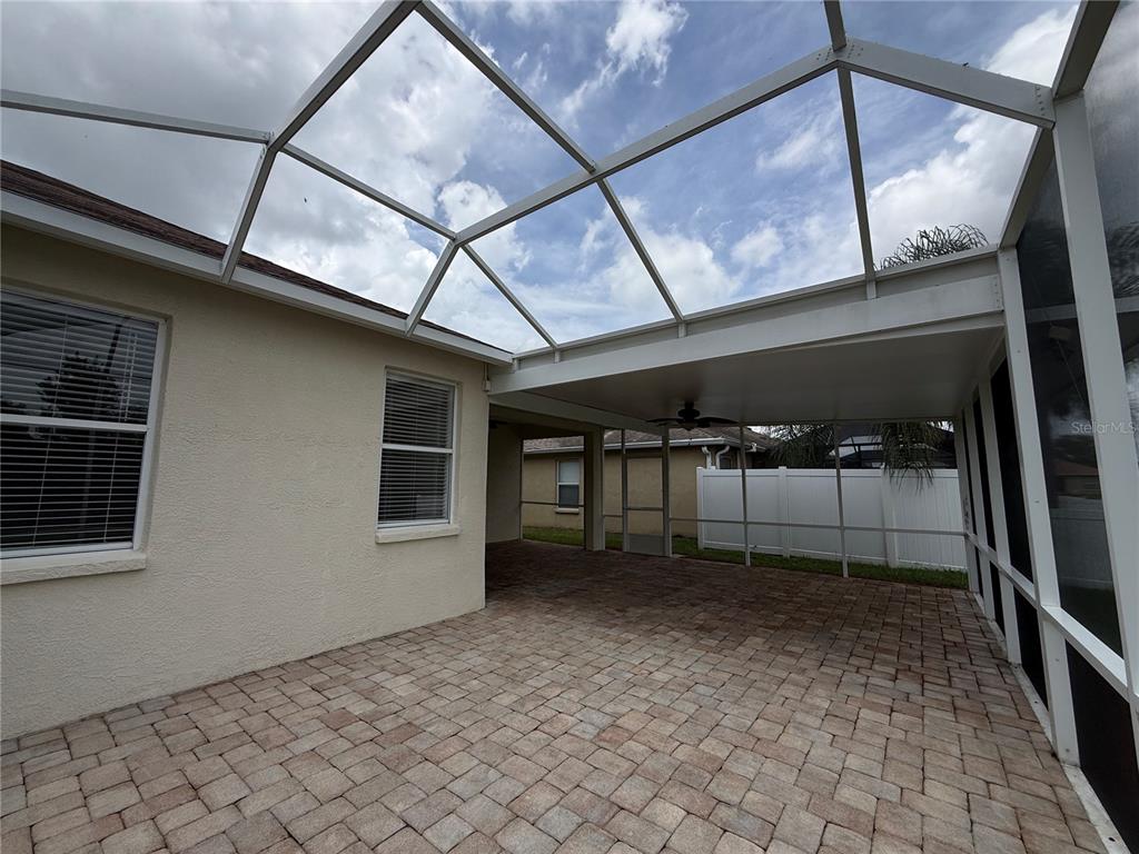 A screened-in patio with paver flooring and a covered section featuring a ceiling fan — 3806 WASHBURN PLACE, WESLEY CHAPEL, FL