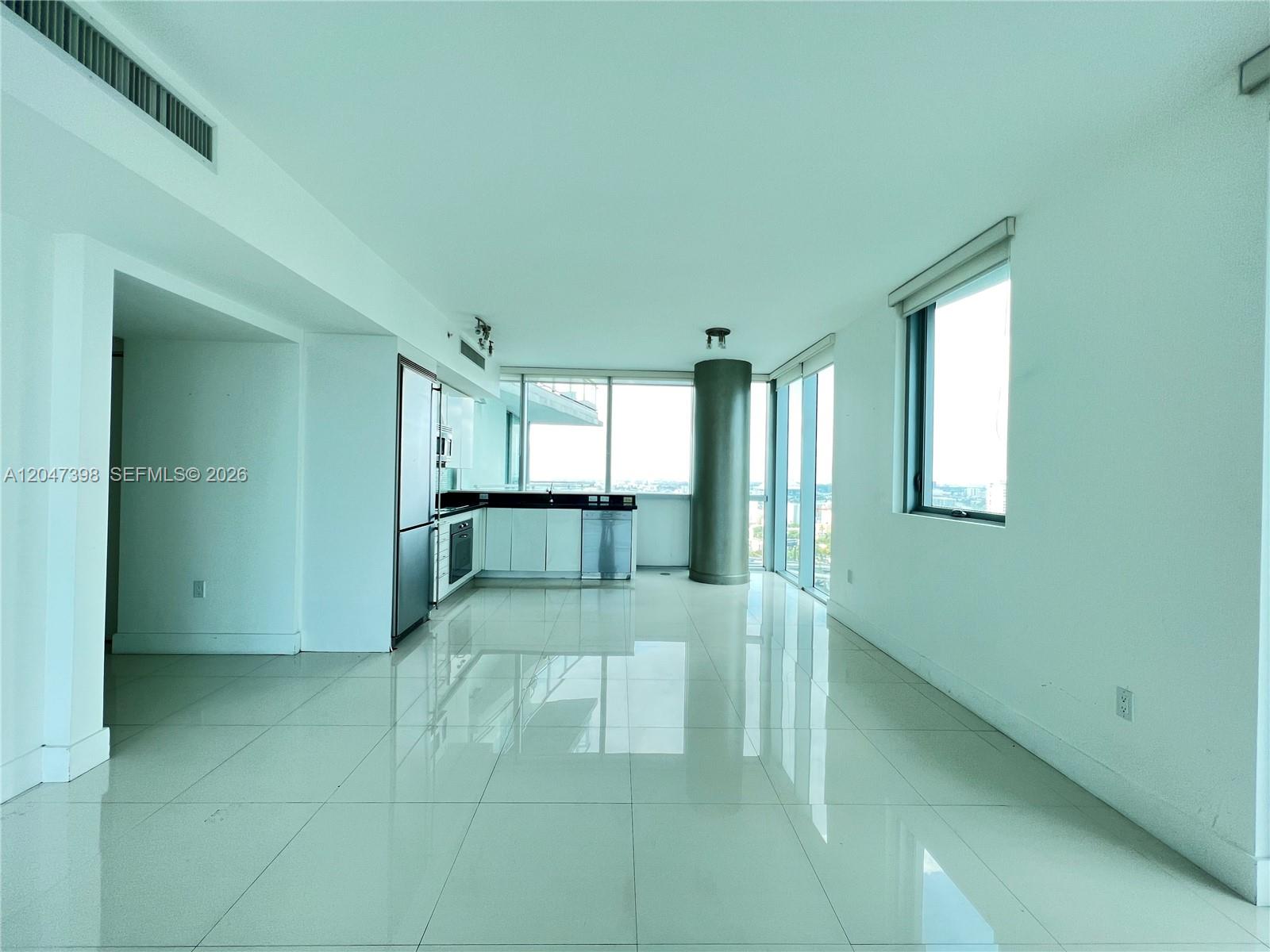 A modern, open-concept kitchen and living area features white tile flooring and floor-to-ceiling windows — 92 SW 3rd St # 3310, Miami FL 33130, MIAMI, FL