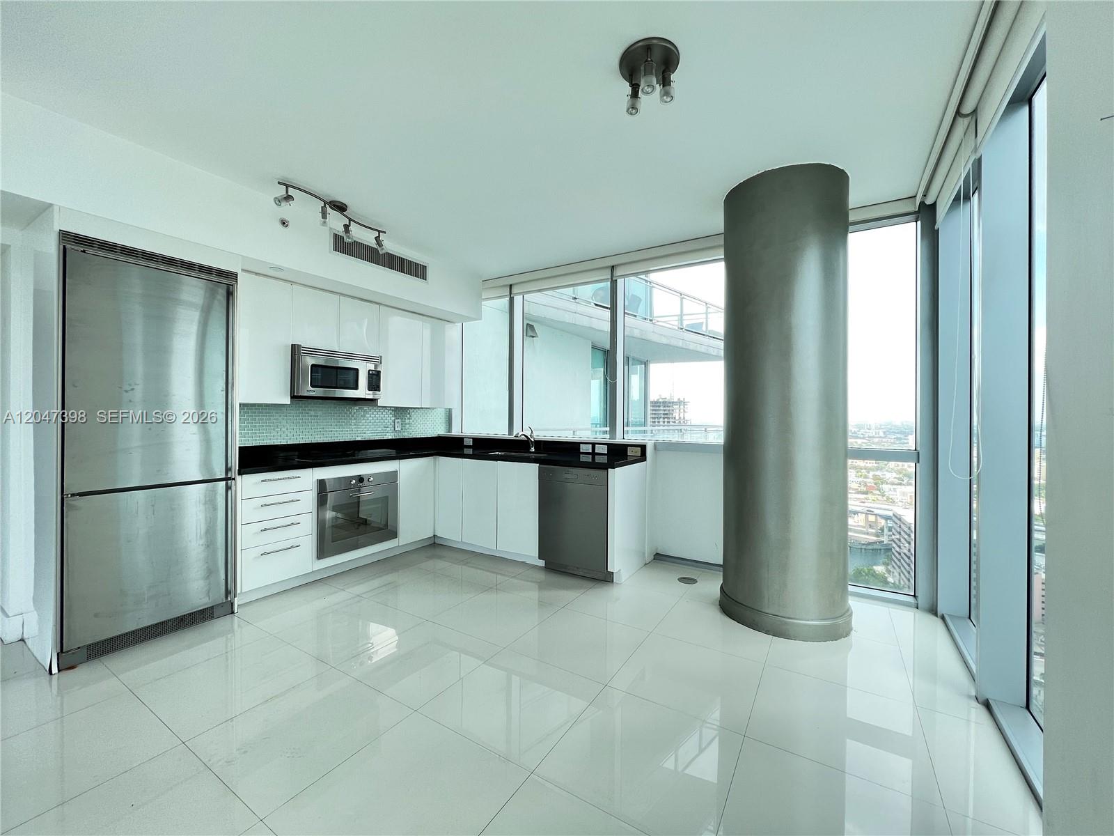 A modern kitchen features white cabinets, stainless steel appliances, and a large structural concrete column — 92 SW 3rd St # 3310, Miami FL 33130, MIAMI, FL