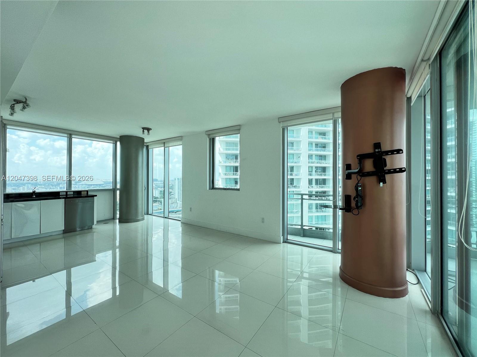 A bright, open-concept living area features white tile floors, floor-to-ceiling windows, and a structural column — 92 SW 3rd St # 3310, Miami FL 33130, MIAMI, FL