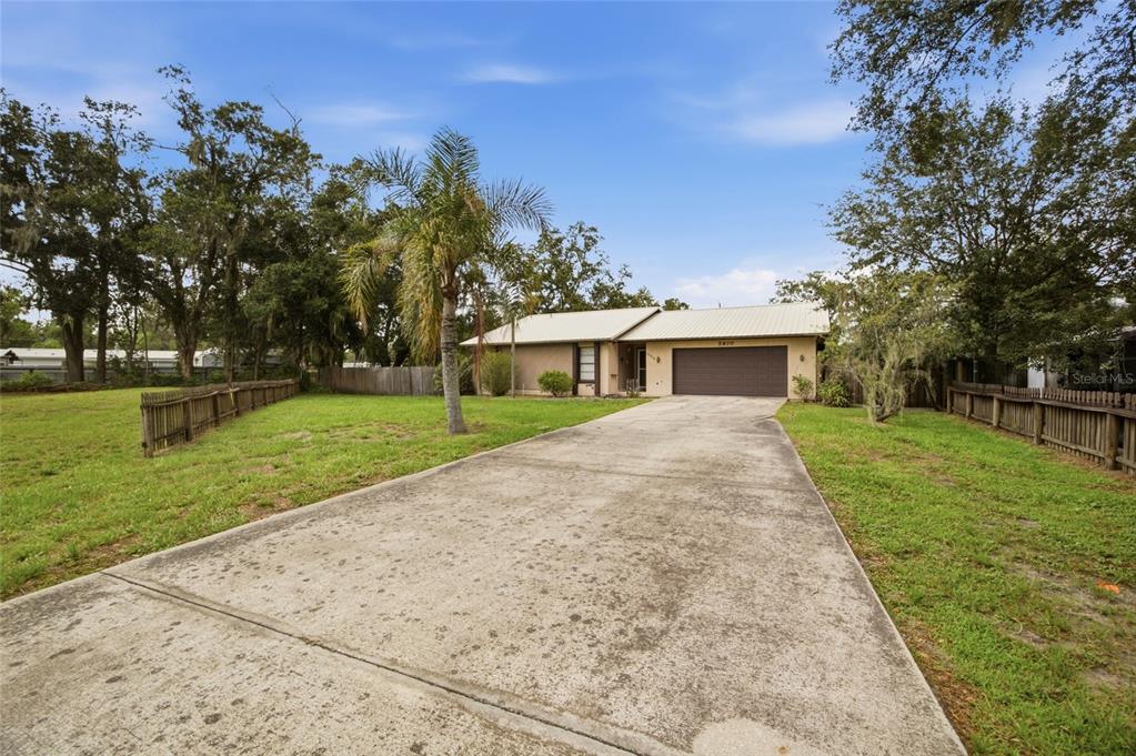 A single-story house with a metal roof and a long concrete driveway — 5970 SOUTHWIND DRIVE, MULBERRY, FL