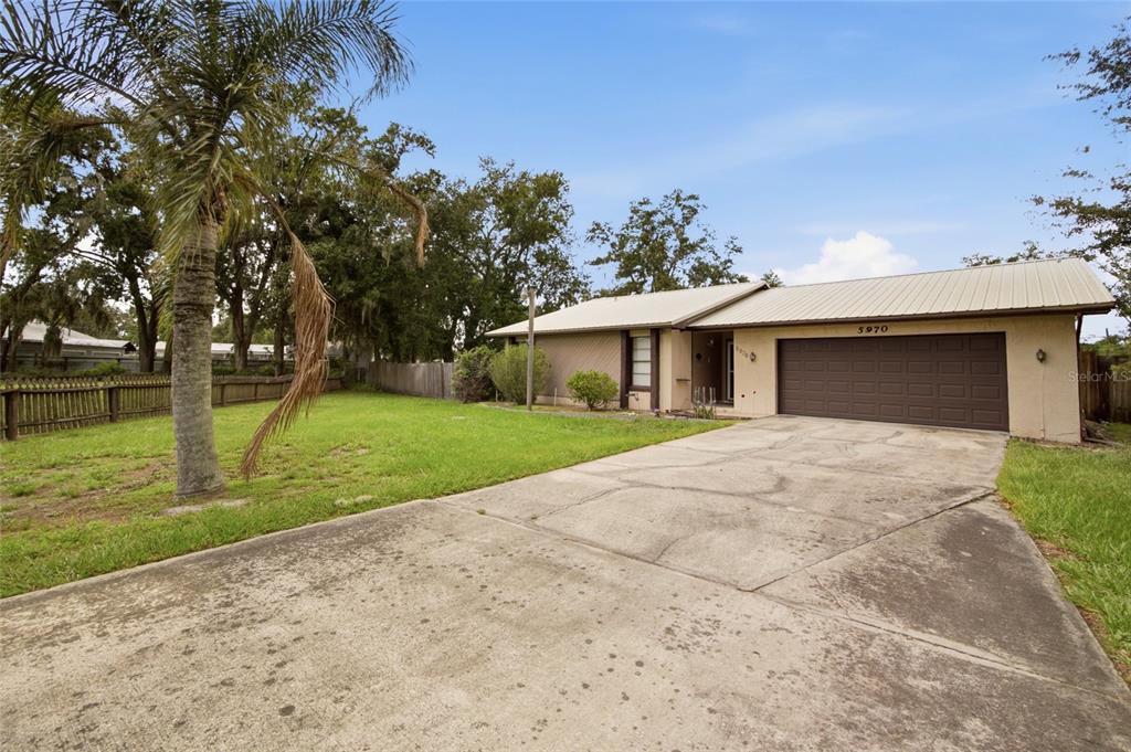 A single-story house with a metal roof, a concrete driveway, and a large front yard — 5970 SOUTHWIND DRIVE, MULBERRY, FL