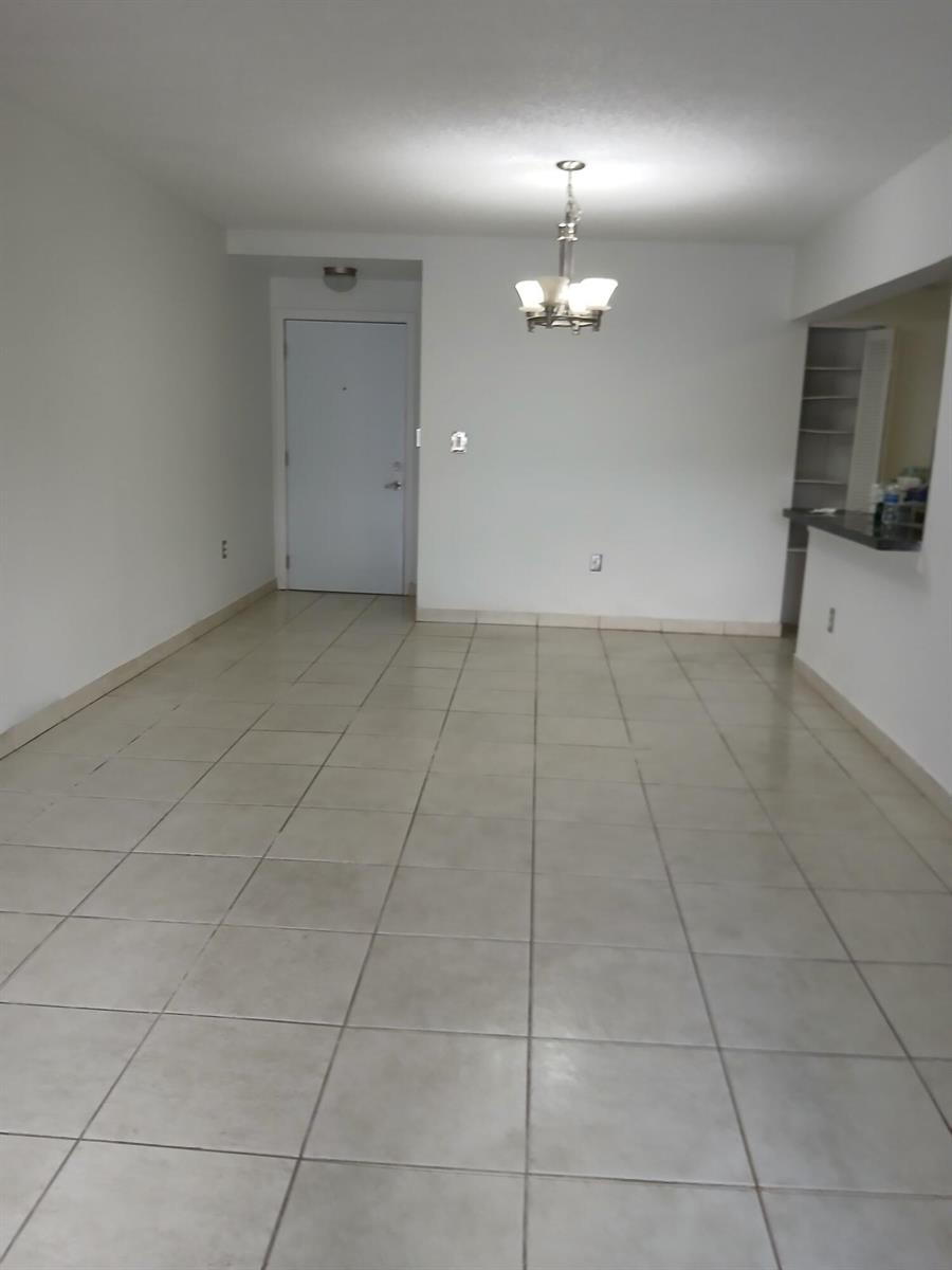 An empty room with light-colored floor tiles, white walls, and a hanging light fixture — 10237 NW 9th St Circle # 4, Miami FL 33172, MIAMI, FL