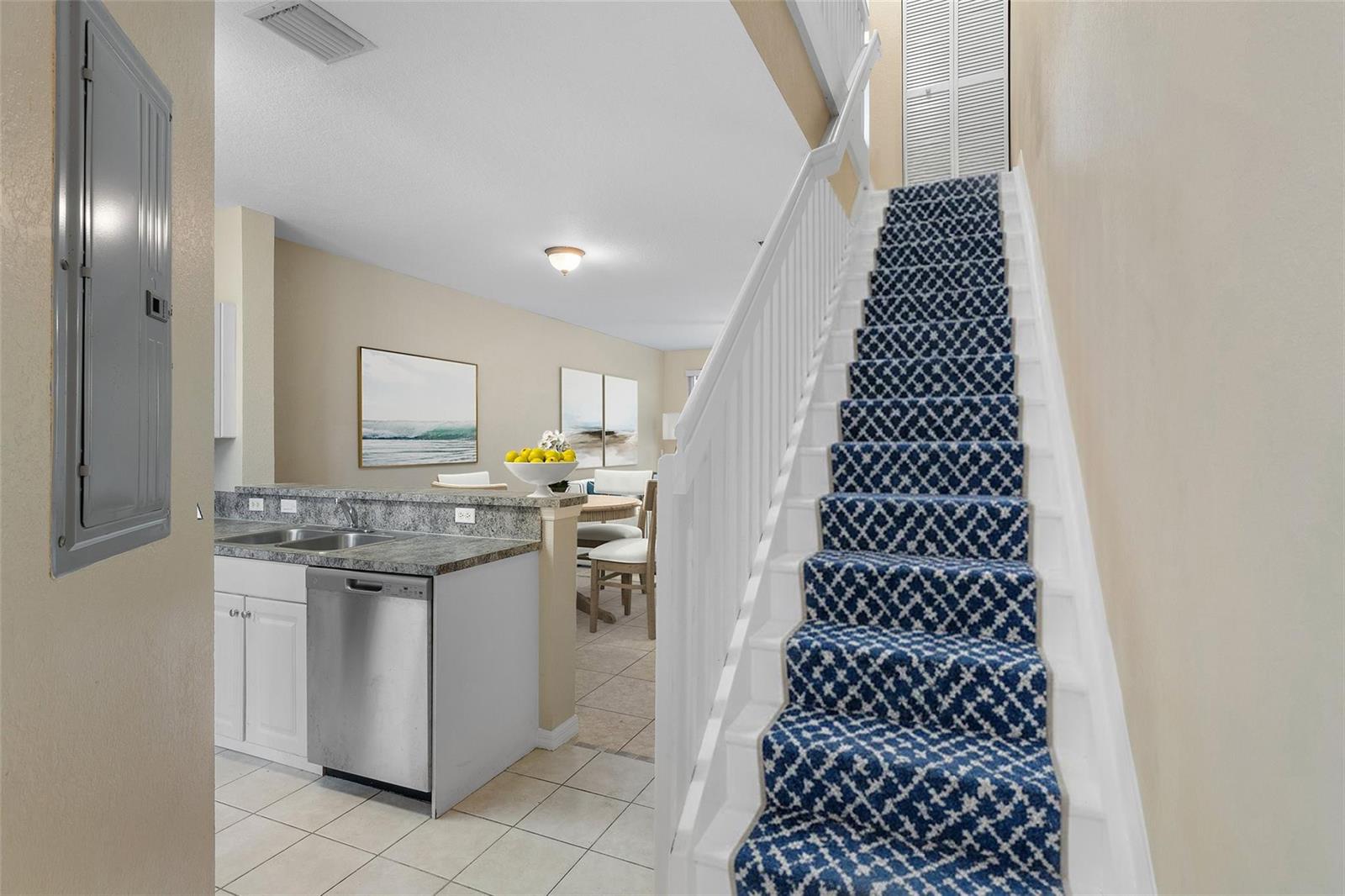 A kitchen with a stainless steel dishwasher and a staircase with a blue patterned runner — 1992 Alamanda Way # 1992, Riviera Beach FL 33404, RIVIERA BEACH, FL