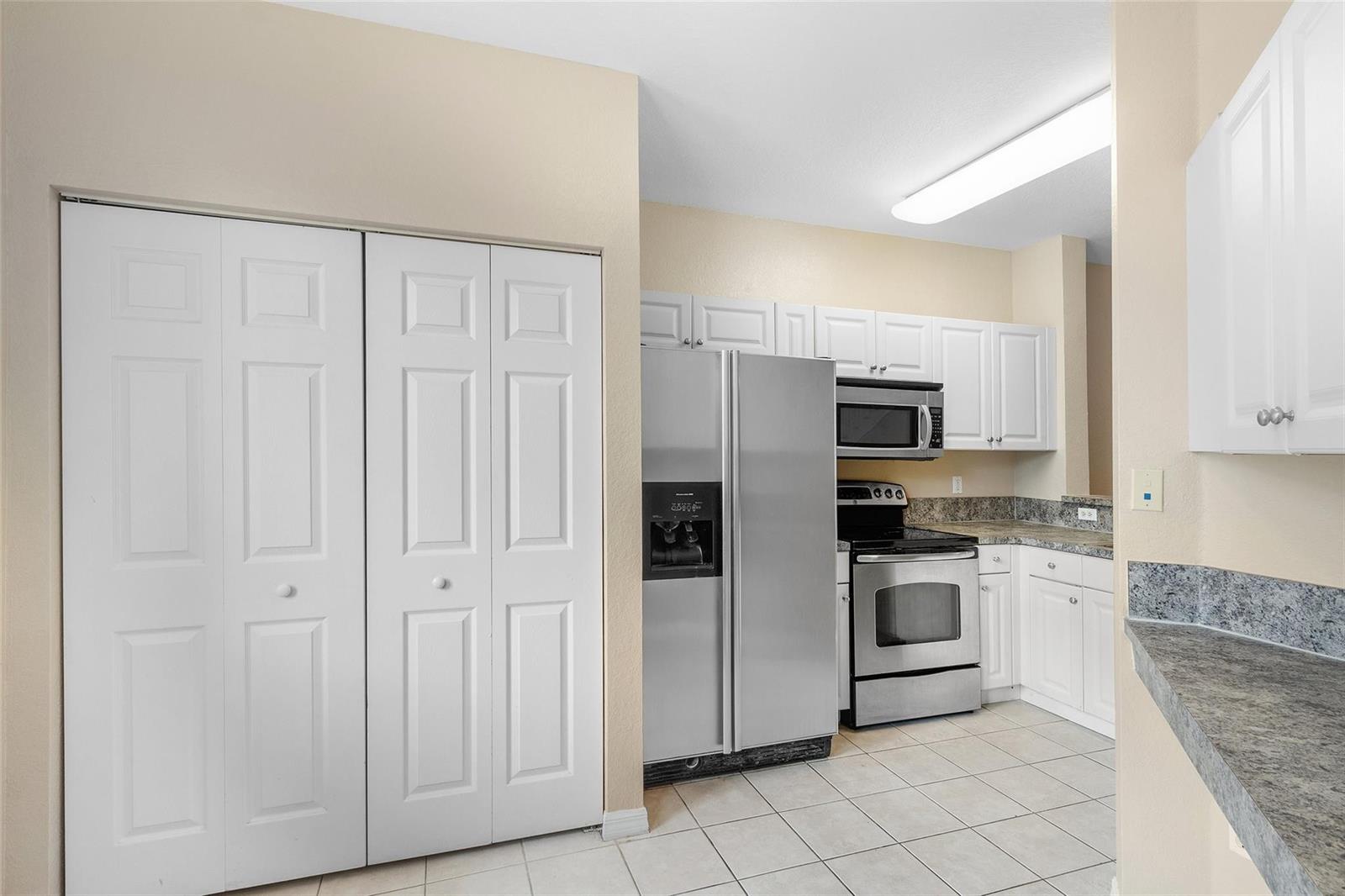 A kitchen features white cabinets, stainless steel appliances, and light-colored tile flooring — 1992 Alamanda Way # 1992, Riviera Beach FL 33404, RIVIERA BEACH, FL