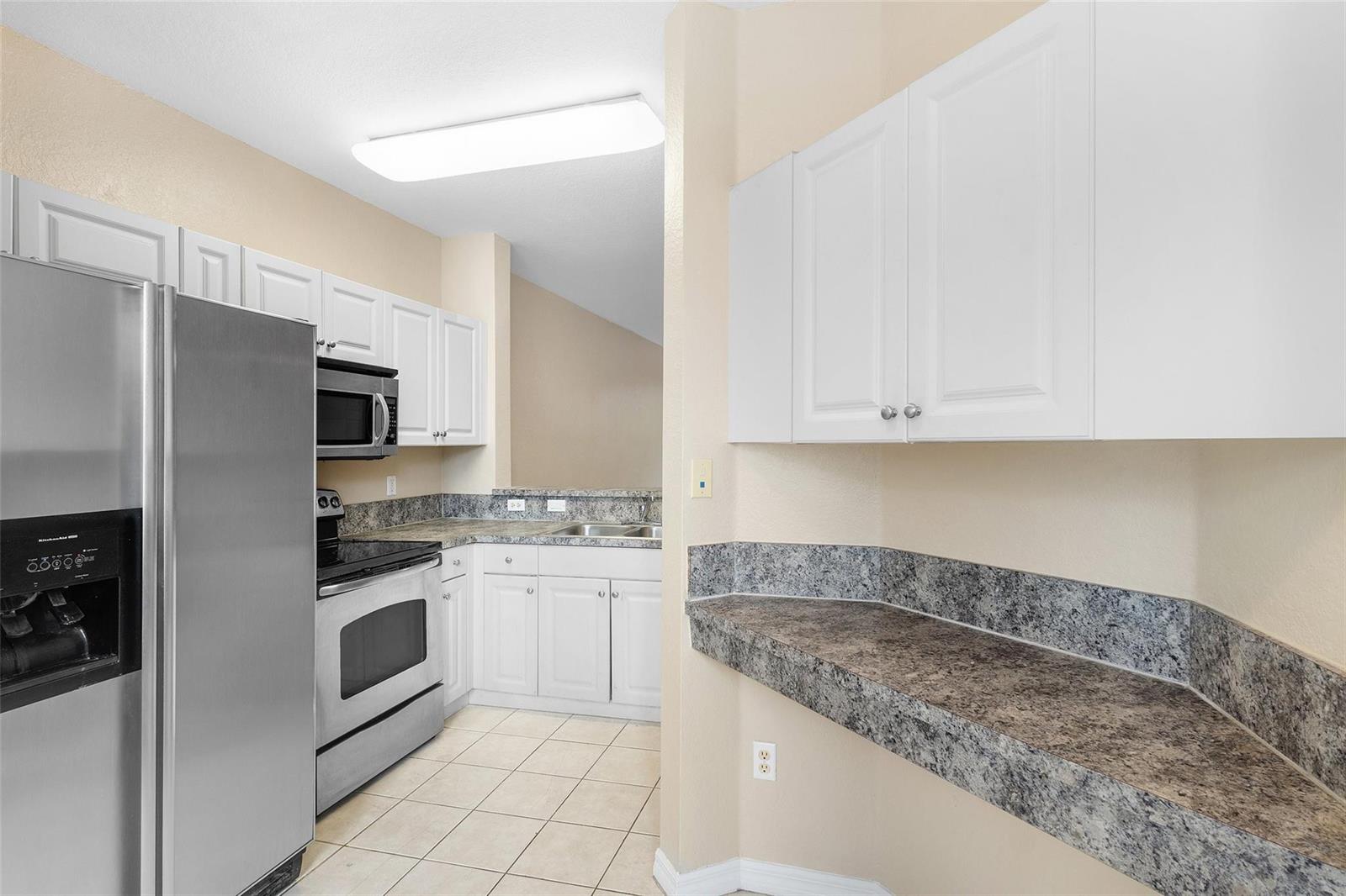 A kitchen features white cabinets, stainless steel appliances, and gray speckled laminate countertops — 1992 Alamanda Way # 1992, Riviera Beach FL 33404, RIVIERA BEACH, FL