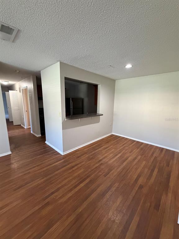 A living room with wood-look flooring features a kitchen pass-through window and a breakfast bar — 2019 DIXIE BELLE DRIVE UNIT 2019D, ORLANDO, FL