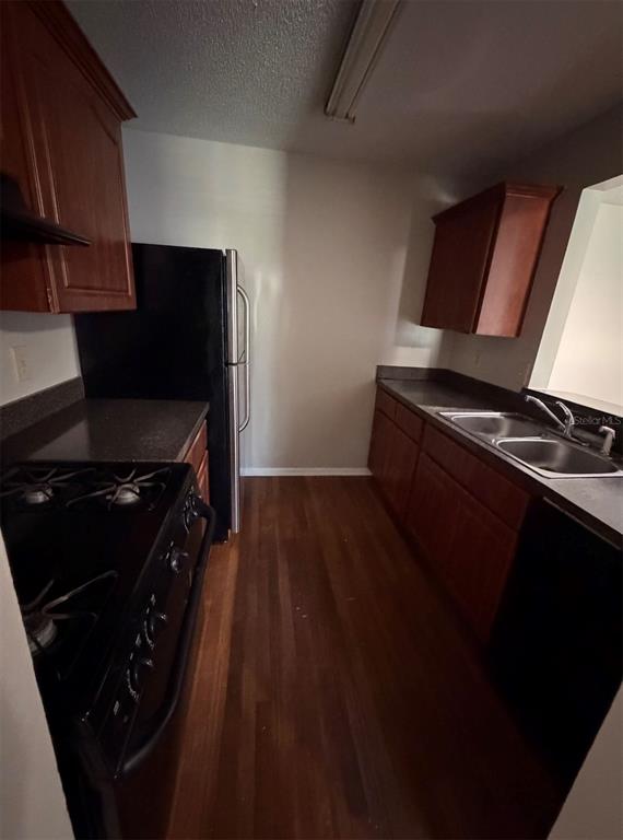 A galley kitchen features wood cabinets, dark countertops, a black stove, and a black refrigerator — 2019 DIXIE BELLE DRIVE UNIT 2019D, ORLANDO, FL
