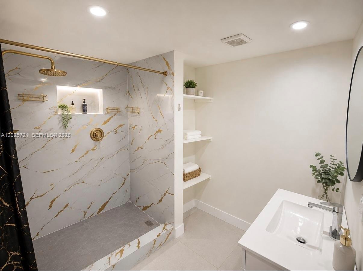 A bathroom features a walk-in shower with gold-veined marble tile, gold fixtures, and open shelving — 4125 N 32nd Ct, Hollywood FL 33021, HOLLYWOOD, FL