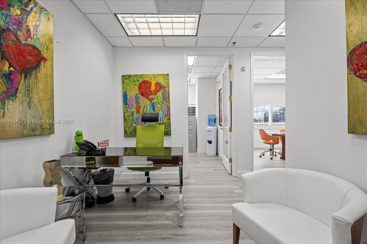 A modern office features a mirrored desk, a lime green chair, and abstract wall art — 848 Brickell Ave, Miami FL 33131, MIAMI, FL
