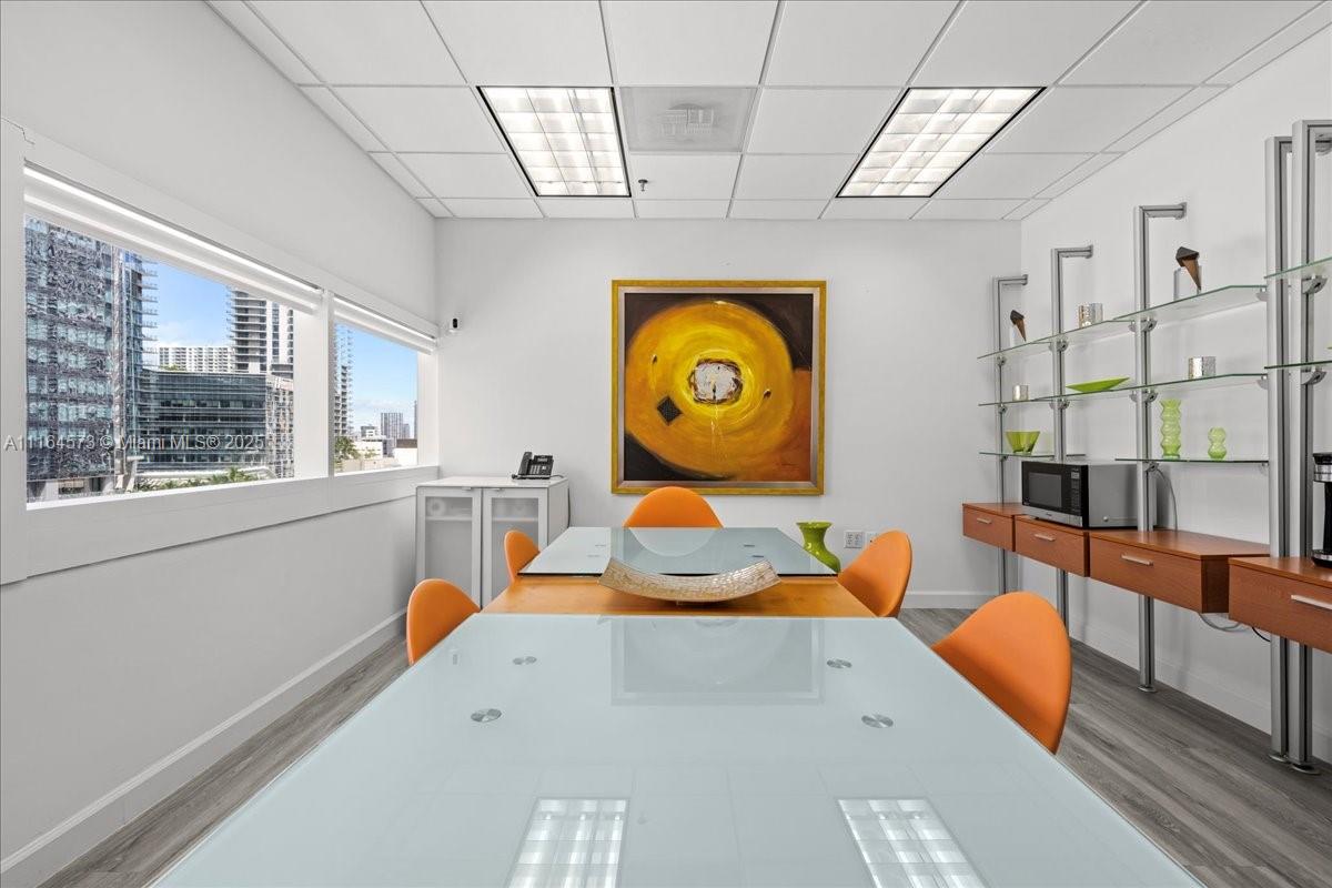 A conference room features a glass-topped table, orange chairs, and a large abstract painting — 848 Brickell Ave, Miami FL 33131, MIAMI, FL