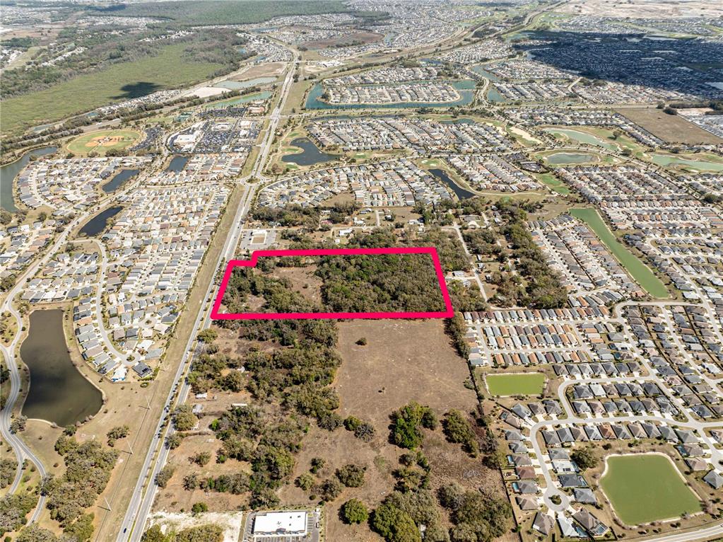 An aerial view shows a rectangular plot of land outlined in pink amidst suburban neighborhoods — 5245 WARM SPRINGS AVENUE, WILDWOOD, FL