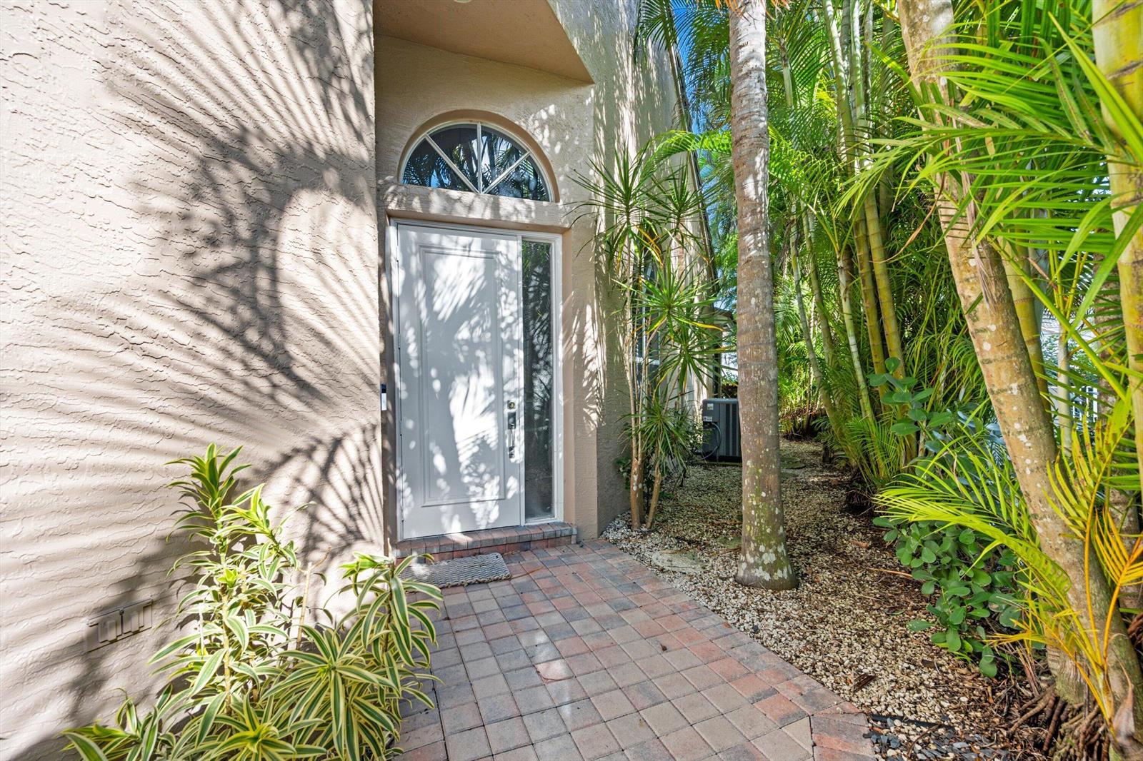 A white front door with a transom window sits at the end of a brick walkway — 4657 Carlton Golf Drive, Lake Worth FL 33449, LAKE WORTH, FL