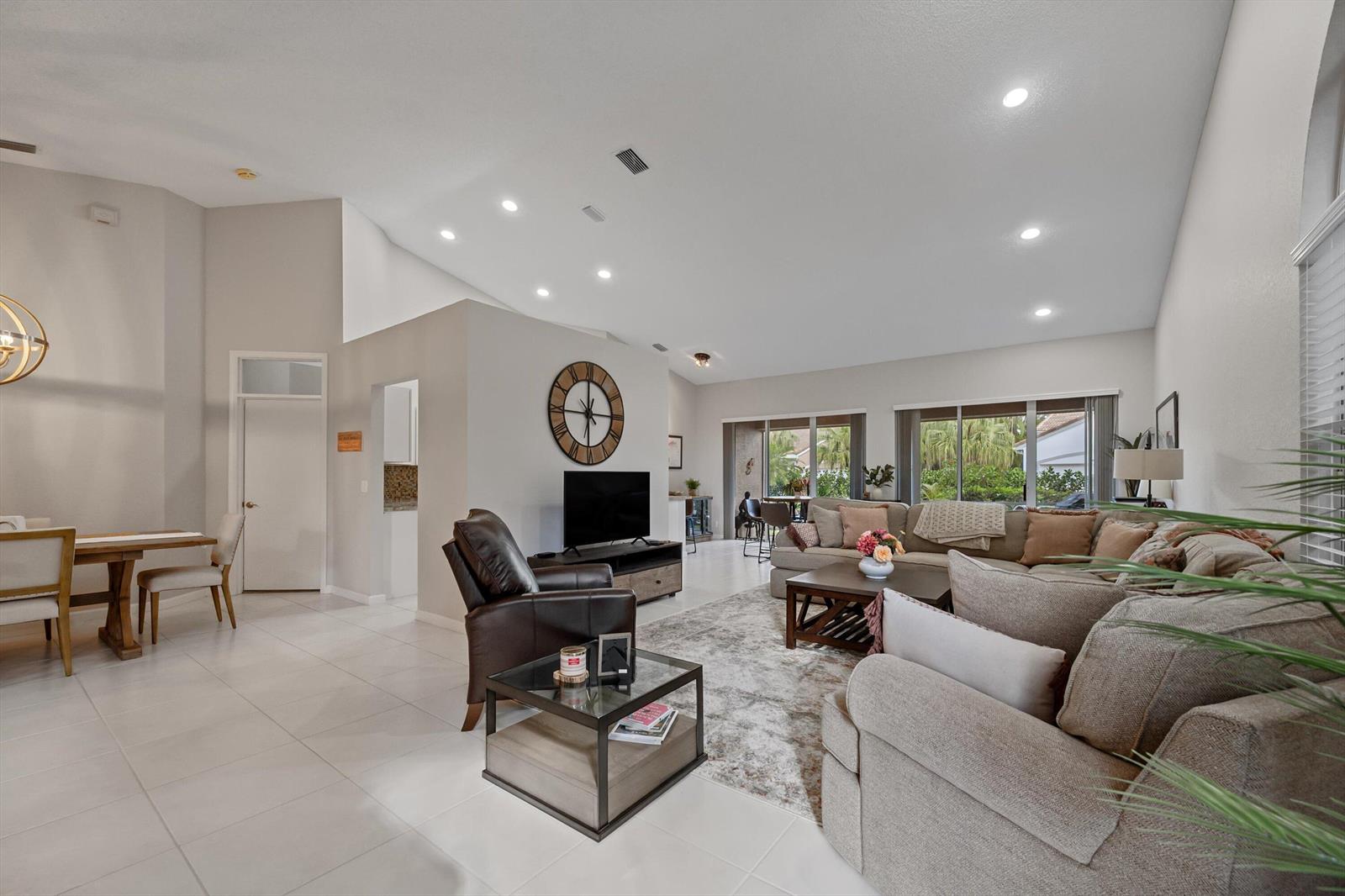 A spacious living room features vaulted ceilings, tile flooring, a large sectional, and a dining area — 4657 Carlton Golf Drive, Lake Worth FL 33449, LAKE WORTH, FL