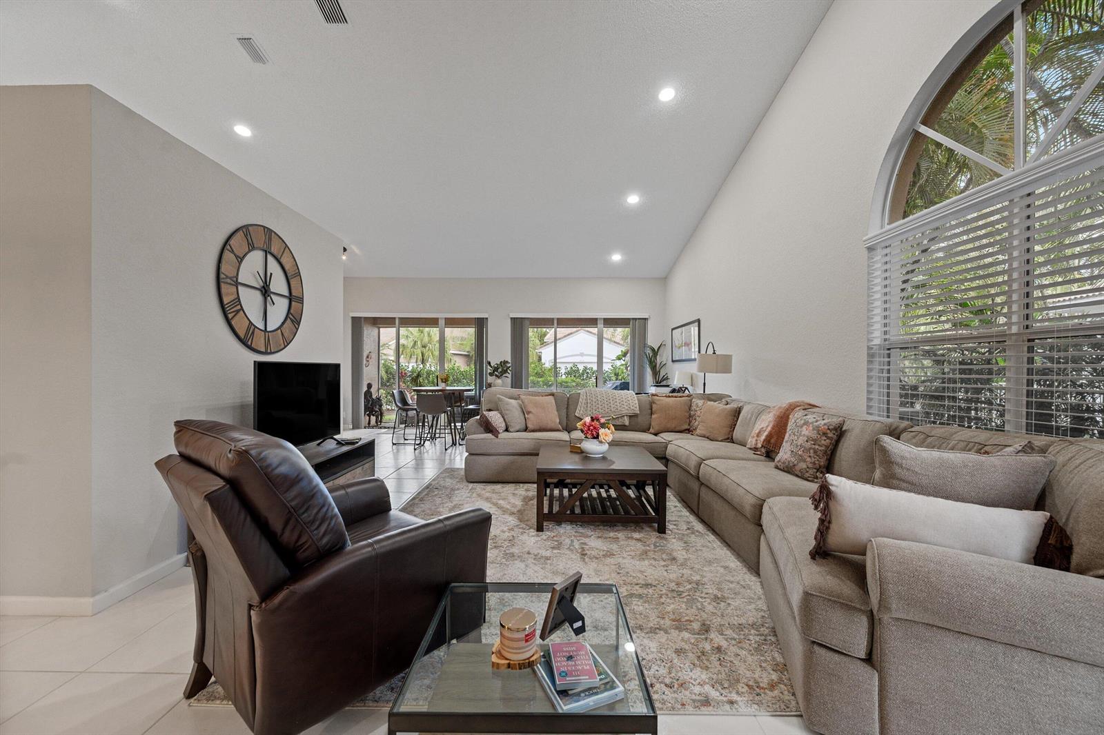 A spacious living room features a large sectional sofa, a leather recliner, and vaulted ceilings — 4657 Carlton Golf Drive, Lake Worth FL 33449, LAKE WORTH, FL