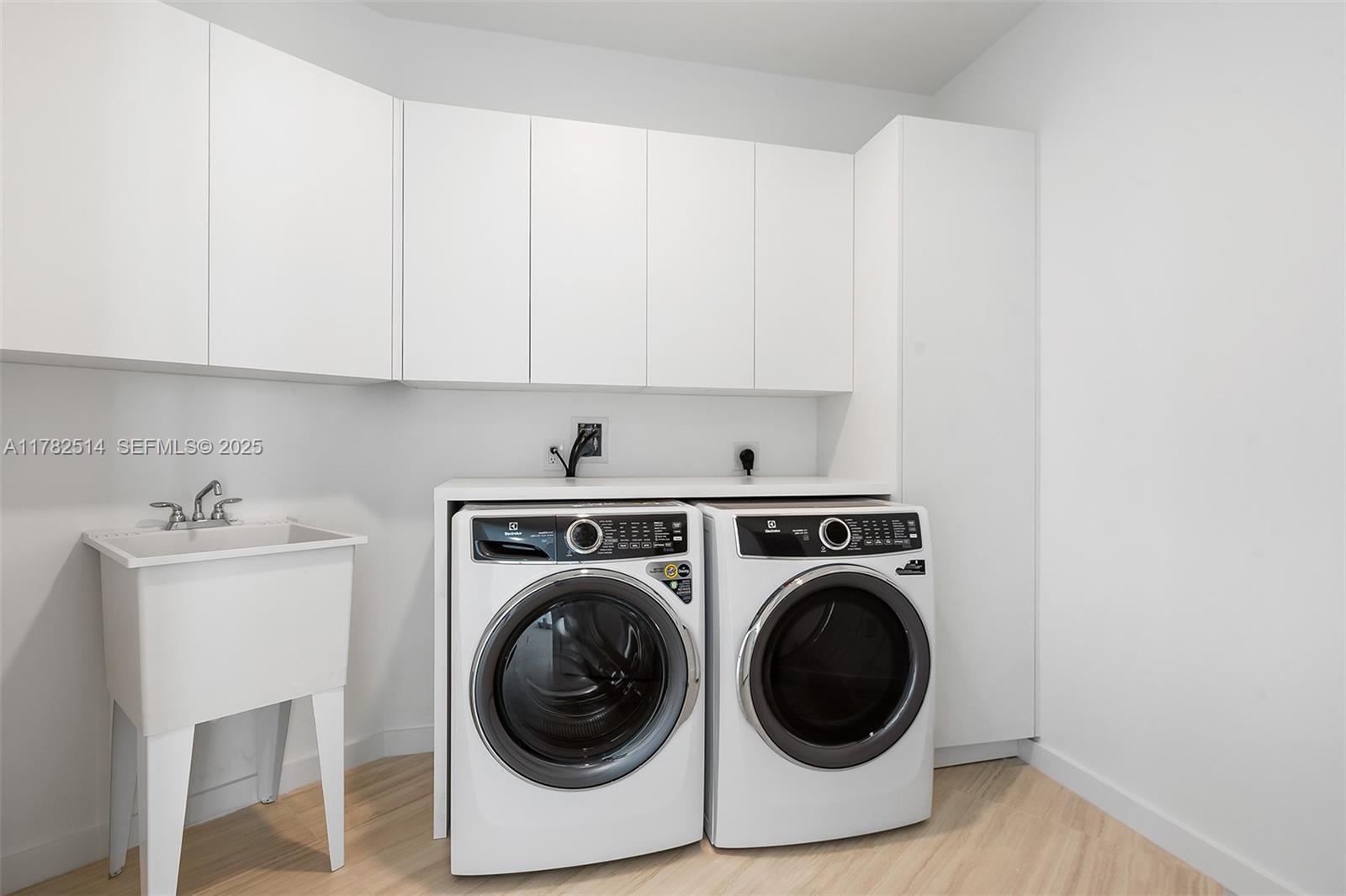 A laundry room features white cabinets, a utility sink, and a washer and dryer set — 851 NE 1st Ave # 5500, Miami FL 33132, MIAMI, FL