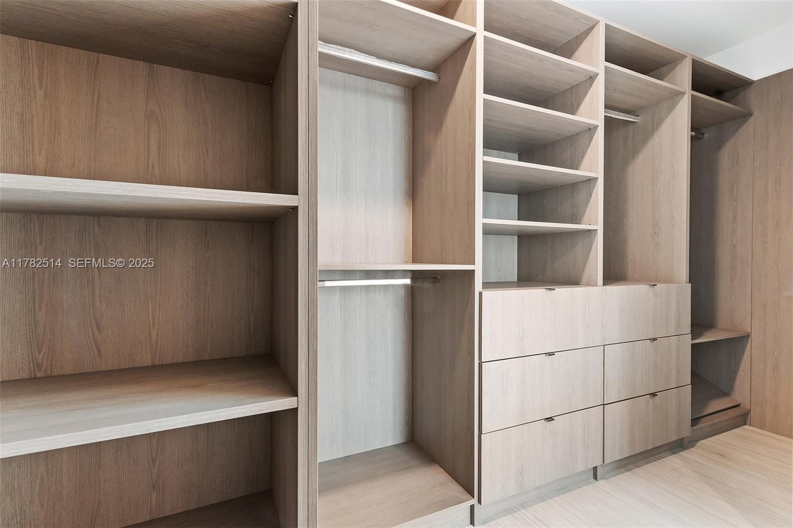 A walk-in closet features light wood shelving, hanging rods, and built-in storage drawers — 851 NE 1st Ave # 5500, Miami FL 33132, MIAMI, FL