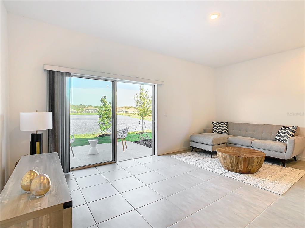A living room with tile floors, a gray sectional sofa, and a sliding door to a patio — 3588 LANDING NET DRIVE, KISSIMMEE, FL