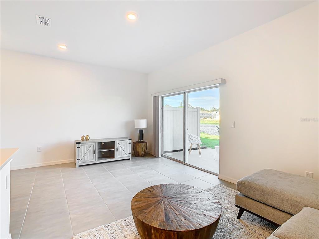 A living room features light tile flooring, a wooden coffee table, and a sliding glass door — 3588 LANDING NET DRIVE, KISSIMMEE, FL