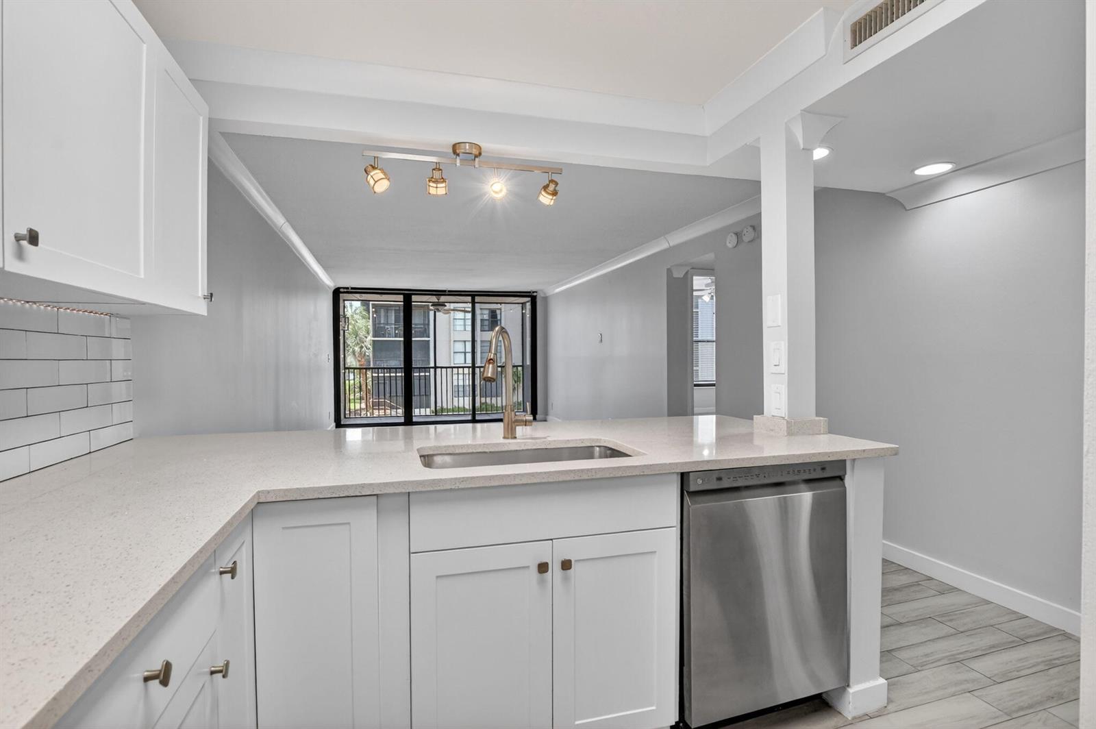 A kitchen with white cabinets, quartz countertops, stainless steel appliances, and a view of balconies — 8 Royal Palm Way # 203, Boca Raton FL 33432, BOCA RATON, FL