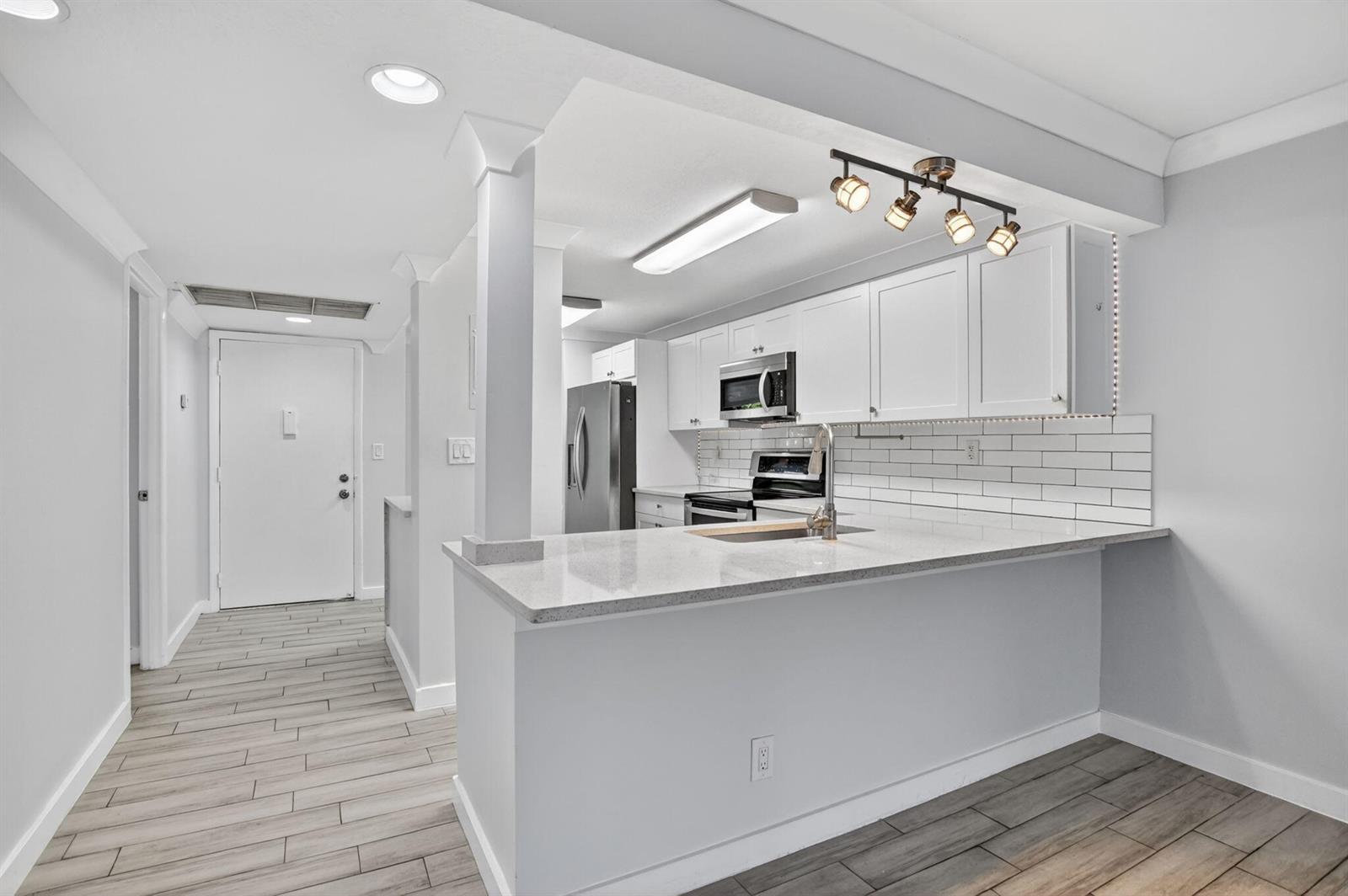 A kitchen with white cabinets, stainless steel appliances, and a granite-topped breakfast bar — 8 Royal Palm Way # 203, Boca Raton FL 33432, BOCA RATON, FL