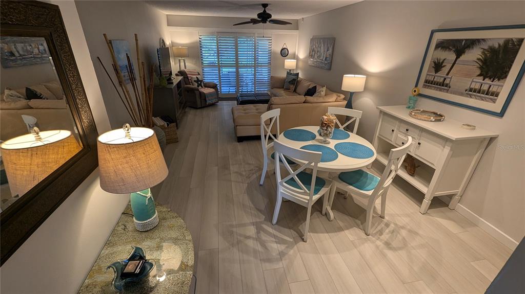 A living and dining area features light wood-look flooring, a round table, and neutral furniture — 1624 STICKNEY POINT UNIT 107, SARASOTA, FL
