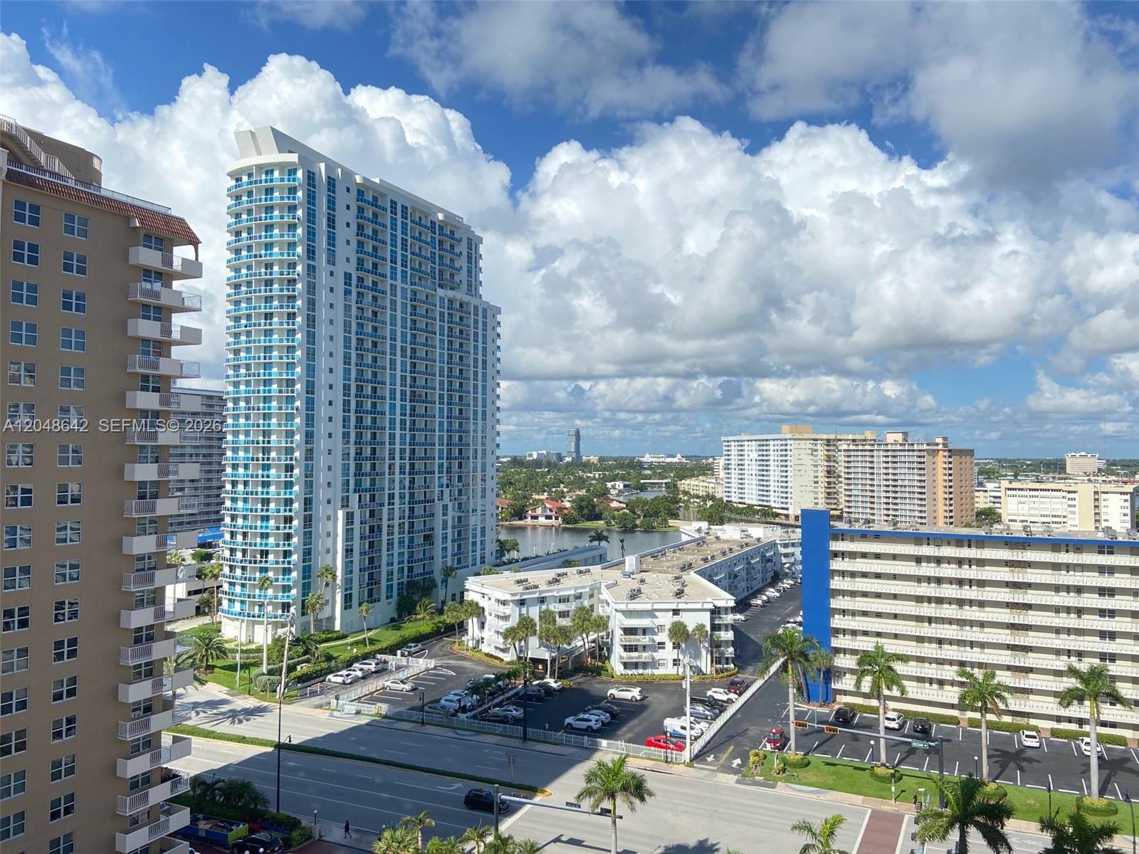 An elevated view shows several high-rise apartment buildings and a parking lot under a cloudy sky — 1904 S Ocean Dr # 1607, Hallandale Beach FL 33009, HALLANDALE BEACH, FL