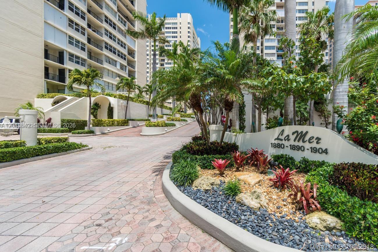 A paved driveway leads to the entrance of a multi-story apartment complex with landscaping — 1904 S Ocean Dr # 1607, Hallandale Beach FL 33009, HALLANDALE BEACH, FL