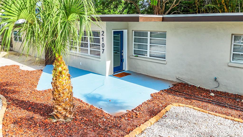 A single-story house exterior features a blue painted porch, a palm tree, and white walls — 2107 PINE TERRACE, SARASOTA, FL
