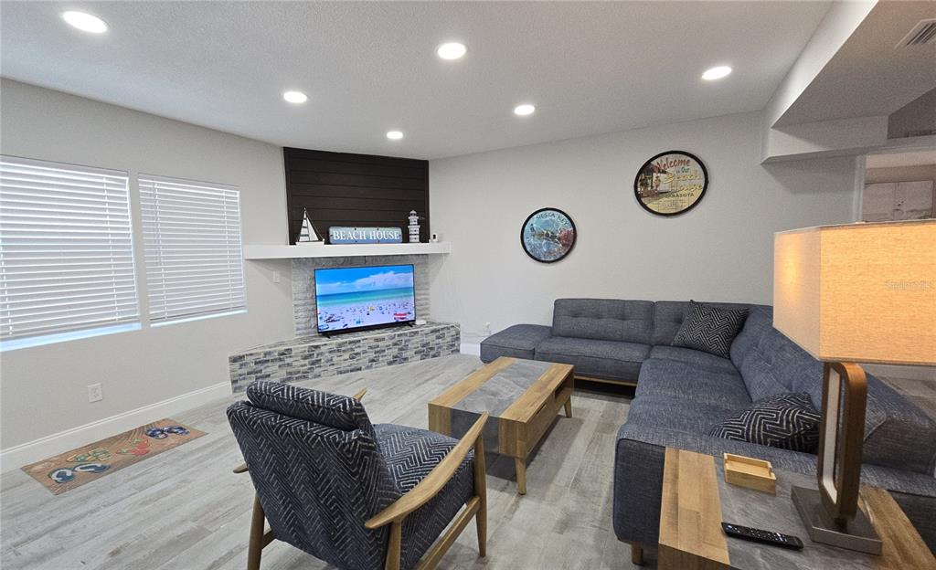 A living room features a brick fireplace, a sectional sofa, and a patterned armchair — 2107 PINE TERRACE, SARASOTA, FL