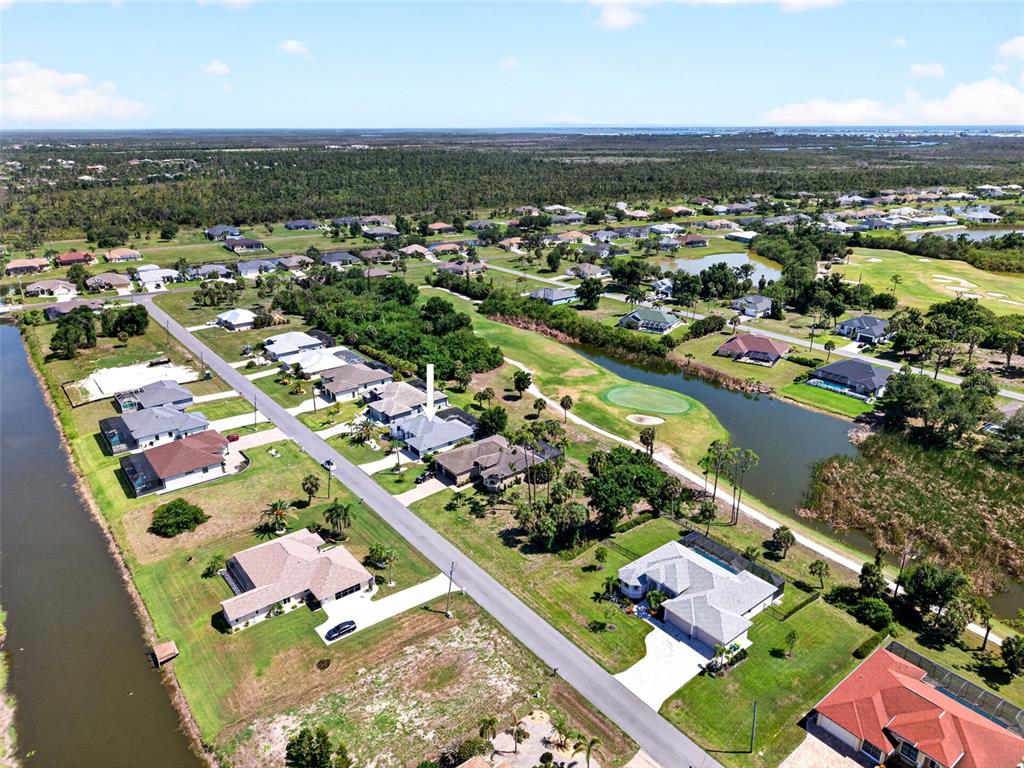 An aerial view shows a residential neighborhood with houses, a golf course, and a canal — 16 TOURNAMENT ROAD, ROTONDA WEST, FL