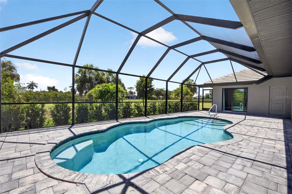A swimming pool with a paved deck is enclosed by a screened lanai — 16 TOURNAMENT ROAD, ROTONDA WEST, FL