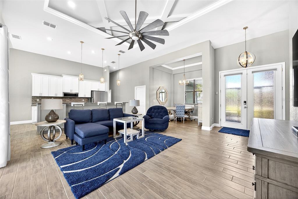 An open-concept living room and kitchen featuring a blue sectional sofa, area rug, and tile flooring — 16 TOURNAMENT ROAD, ROTONDA WEST, FL