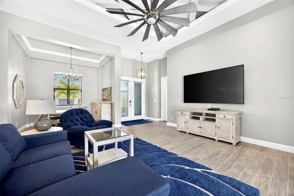 A living room features a large blue sectional, a television, and a windmill-style ceiling fan — 16 TOURNAMENT ROAD, ROTONDA WEST, FL