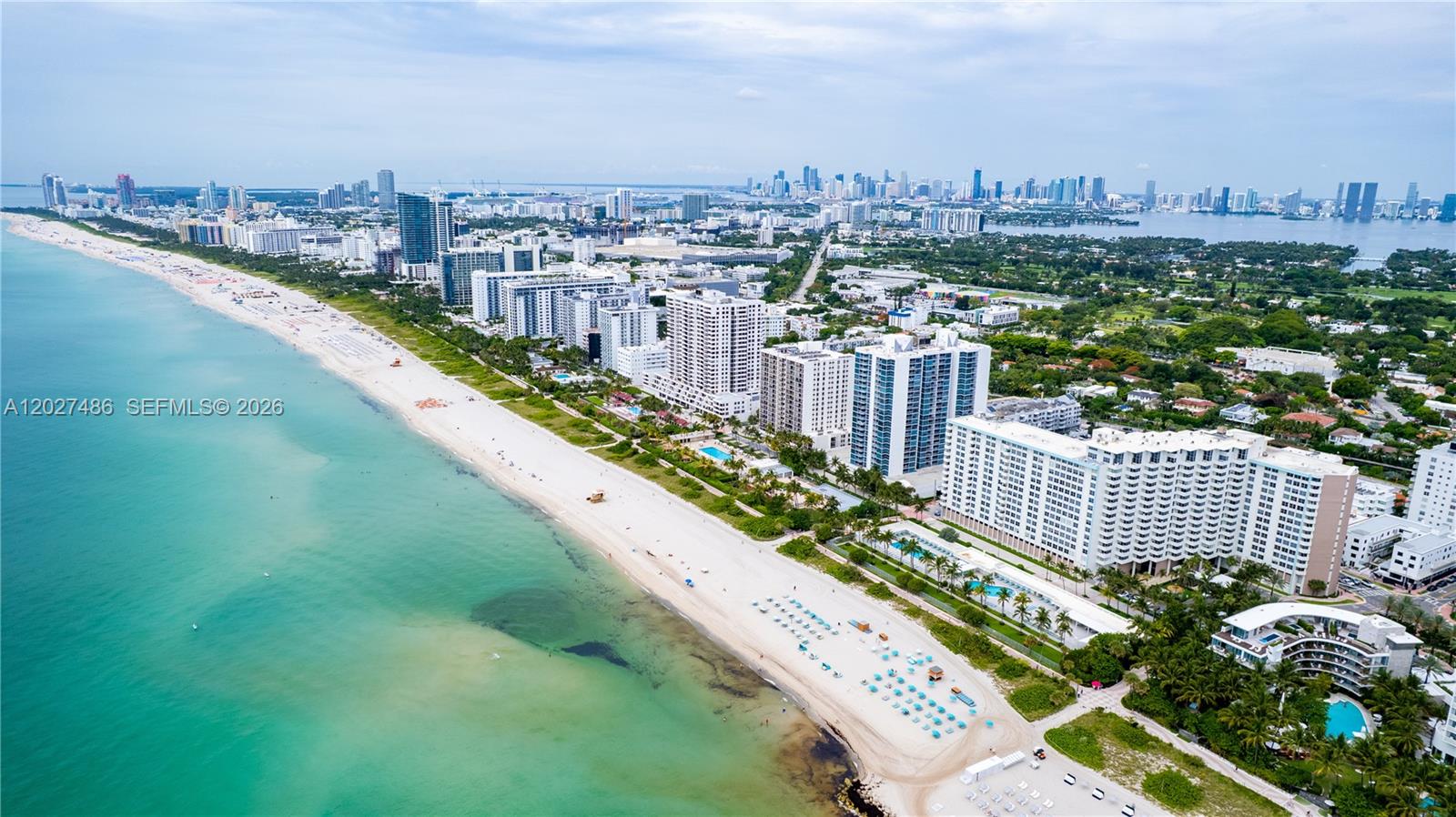 An aerial view shows a sandy beach along the oceanfront with high-rise buildings nearby — 2655 Collins Ave # 603, Miami Beach FL 33140, MIAMI BEACH, FL