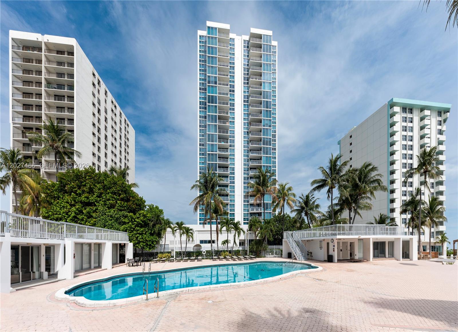 A swimming pool sits on a paved deck in front of three tall residential buildings — 2655 Collins Ave # 603, Miami Beach FL 33140, MIAMI BEACH, FL