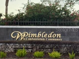 A sign for Wimbledon A Condominium Community stands in front of a dark fence and bushes — 3240 S SEMORAN BOULEVARD UNIT 14, ORLANDO, FL