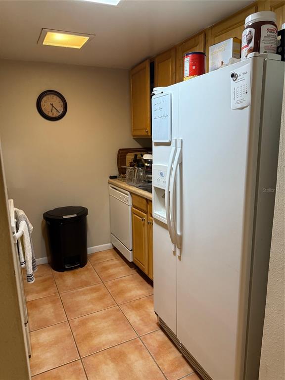 A kitchen features light wood cabinets, a white refrigerator, a dishwasher, and tiled flooring — 3240 S SEMORAN BOULEVARD UNIT 14, ORLANDO, FL