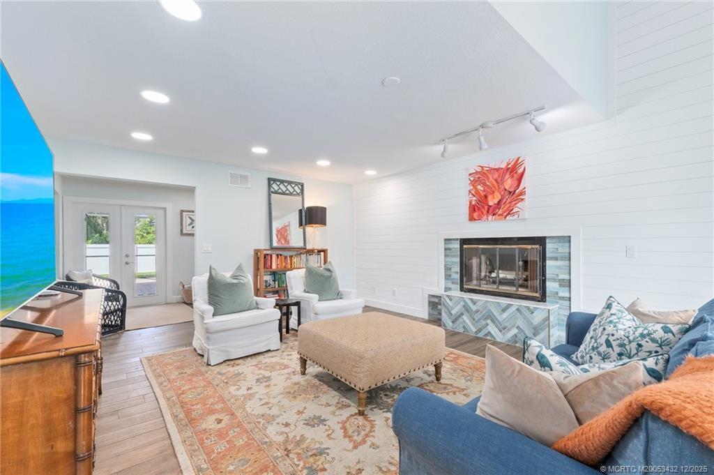 A living room features a fireplace with blue tile, white shiplap walls, and wood flooring — 4304 SE Fairway E, Stuart FL 34997, STUART, FL