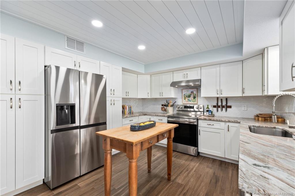 A kitchen with white cabinets, stainless steel appliances, a wood island, and plank-style ceiling — 4304 SE Fairway E, Stuart FL 34997, STUART, FL