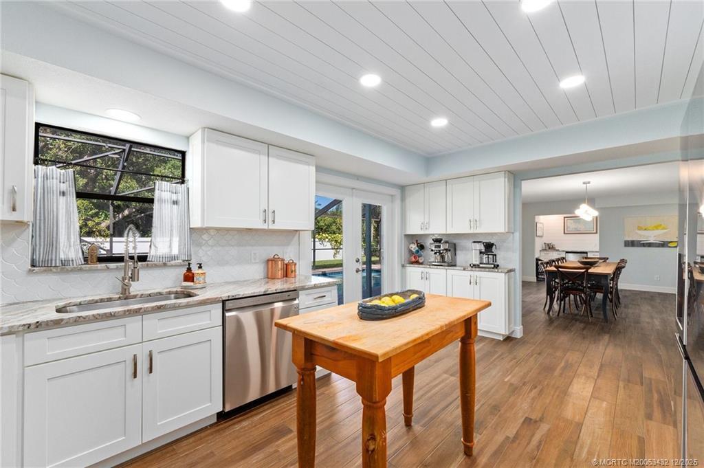 A kitchen with white cabinets, a wooden island, and a view of a backyard pool — 4304 SE Fairway E, Stuart FL 34997, STUART, FL